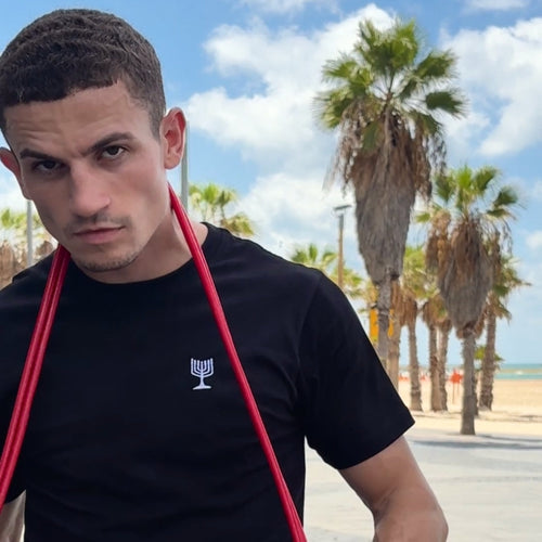 Man holding resistance bands with palm trees and beach in the background
