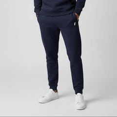 Person wearing navy tracksuit and white sneakers on a light gray background