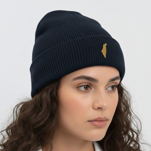 Woman wearing a navy blue beanie with a gold logo on a light gray background