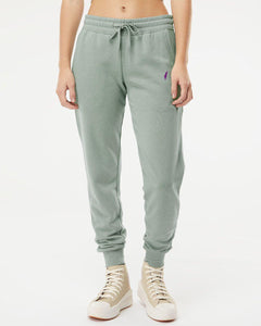 Model wearing sage green Women’s Cali Sweatpants with a drawstring waist, cuffed ankles and a purple thigh logo.