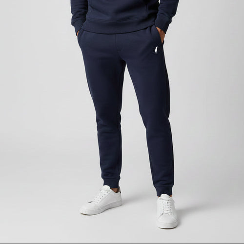 Person wearing navy tracksuit and white sneakers on a light gray background