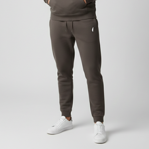 Model wearing dark charcoal Premium Sweatpants with a drawstring waist, white thigh logo and cuffed ankles, styled with white sneakers.